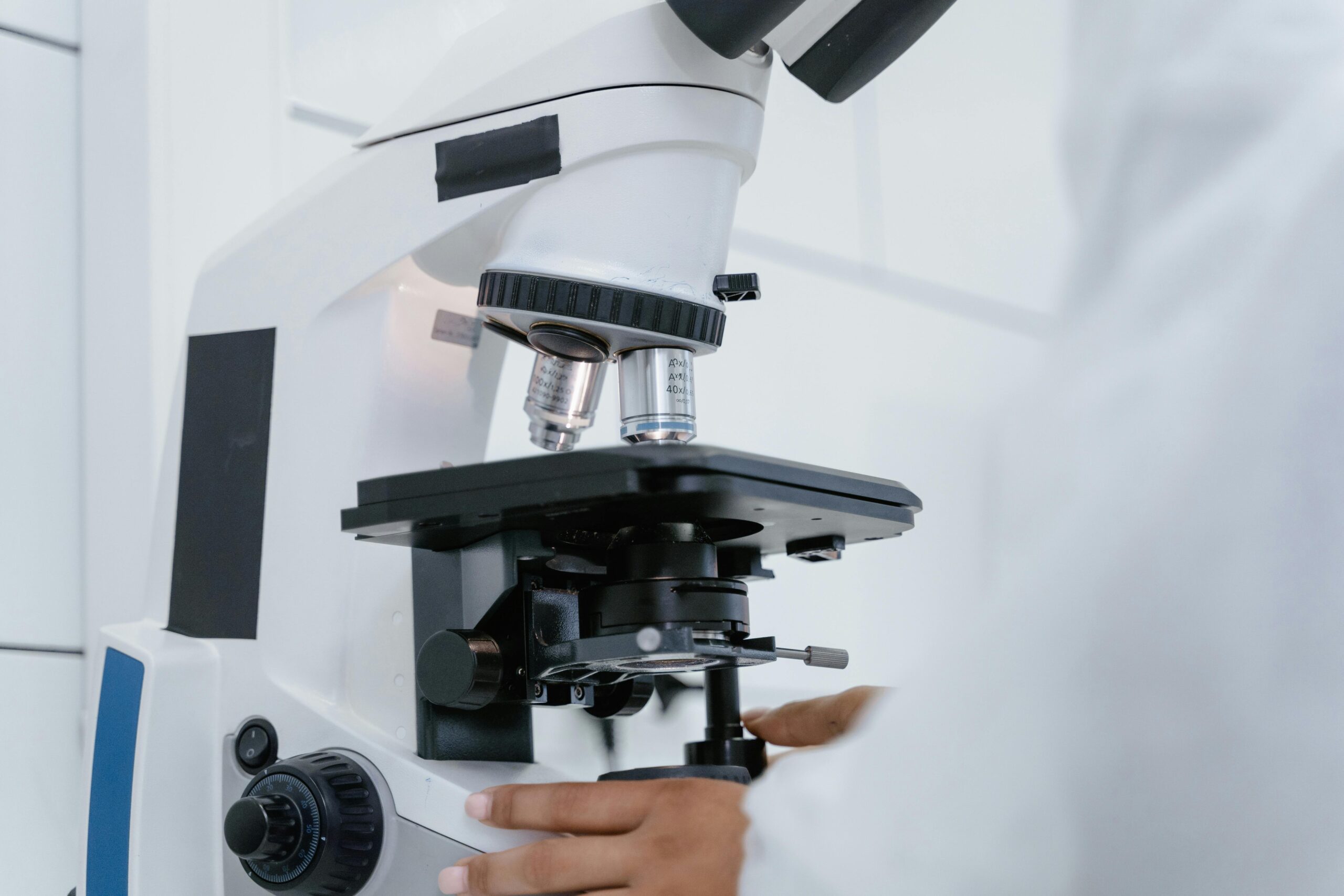 Detailed view of a scientist operating a microscope in a laboratory setting.